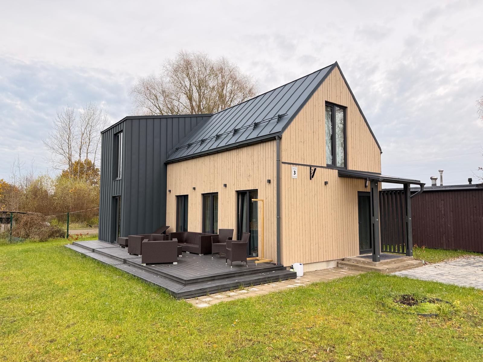 Timber-clad two-storey home with a dark metal roof and garden terrace